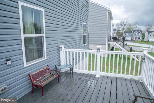 wooden terrace featuring a lawn, stairway, and a residential view