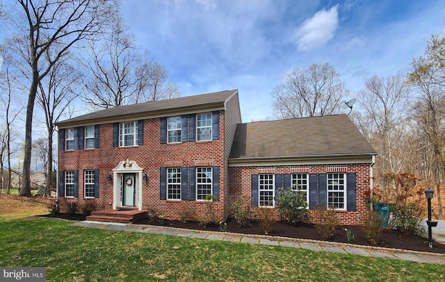 colonial house featuring brick siding and a front lawn