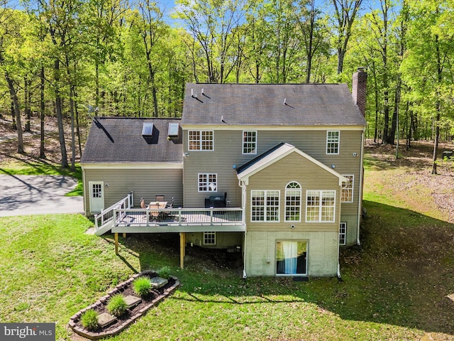 back of house with a chimney, a wooden deck, and a lawn