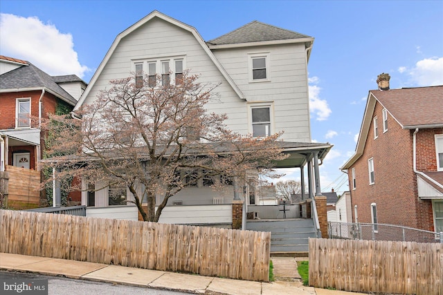 view of front of property with a porch, a shingled roof, and a fenced front yard