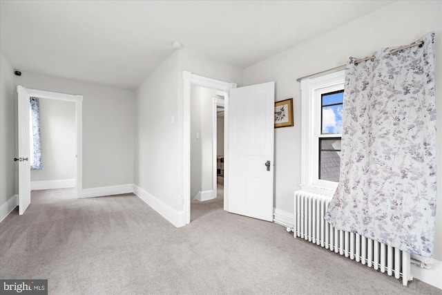 unfurnished bedroom with radiator heating unit, carpet, and baseboards
