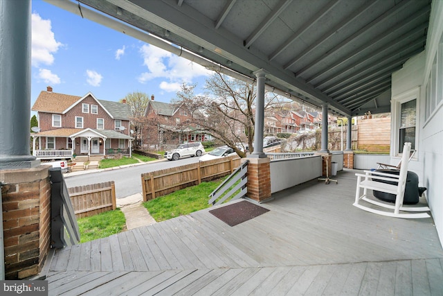 wooden terrace featuring a porch, fence, and a residential view