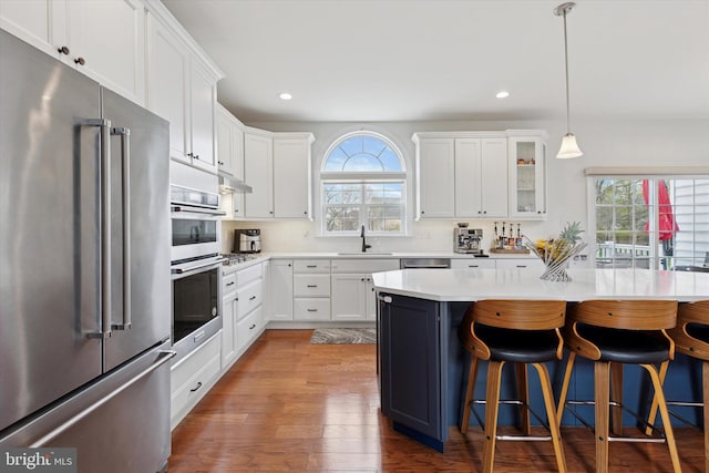kitchen with a sink, recessed lighting, a kitchen breakfast bar, and stainless steel appliances
