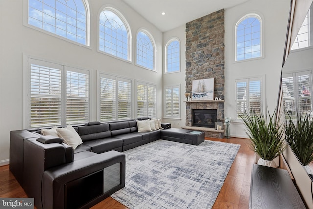 living room featuring wood finished floors, a towering ceiling, and a healthy amount of sunlight