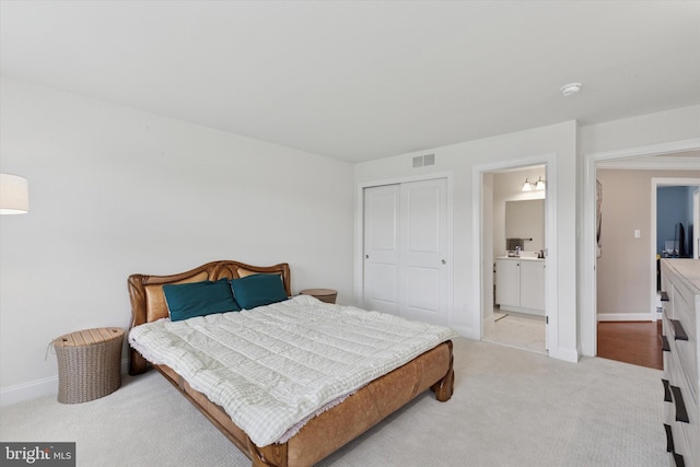 bedroom featuring light carpet, a closet, baseboards, and connected bathroom