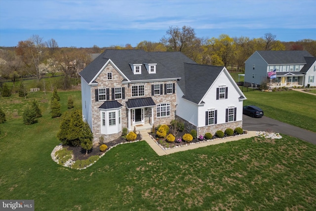 traditional home with a standing seam roof, roof with shingles, metal roof, a front yard, and stone siding