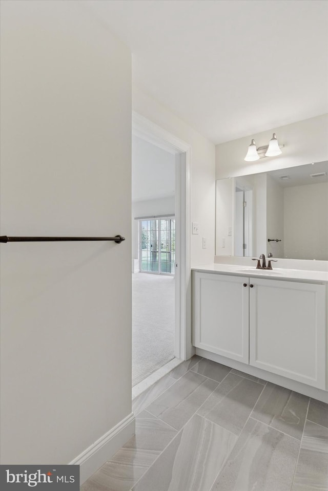 bathroom featuring visible vents, baseboards, marble finish floor, and vanity