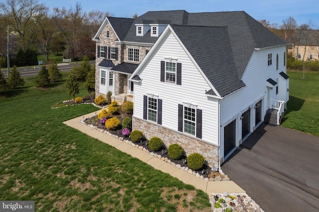 view of side of home with stone siding, an attached garage, aphalt driveway, a shingled roof, and a lawn
