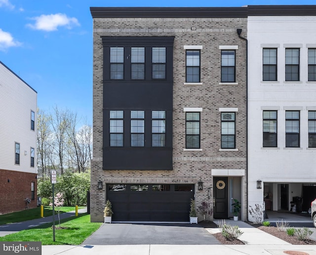 multi unit property with an attached garage, driveway, and brick siding