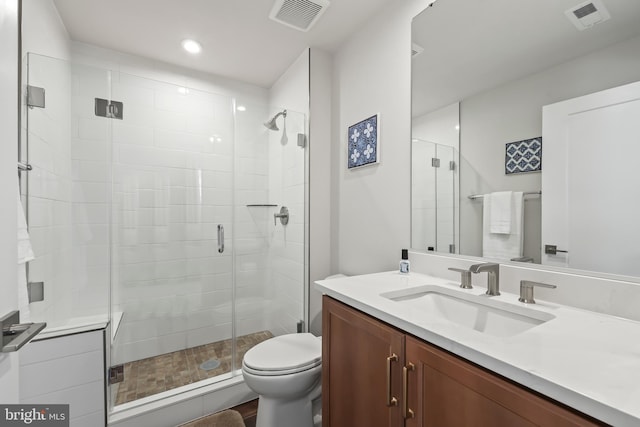 full bath featuring vanity, toilet, visible vents, and a stall shower
