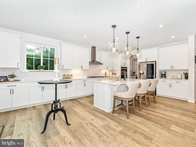 704 Kaplon Ct, Brunswick, MD 21716 - kitchen with wall chimney range hood, backsplash, stainless steel appliances, a breakfast bar area, and light countertops