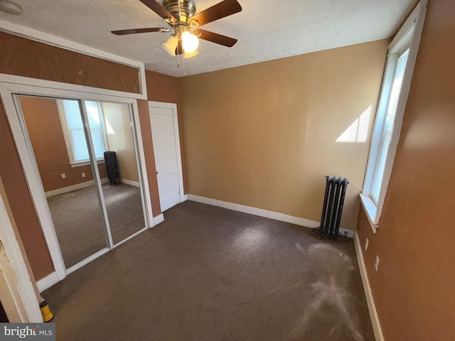 unfurnished bedroom with dark colored carpet, baseboards, and radiator