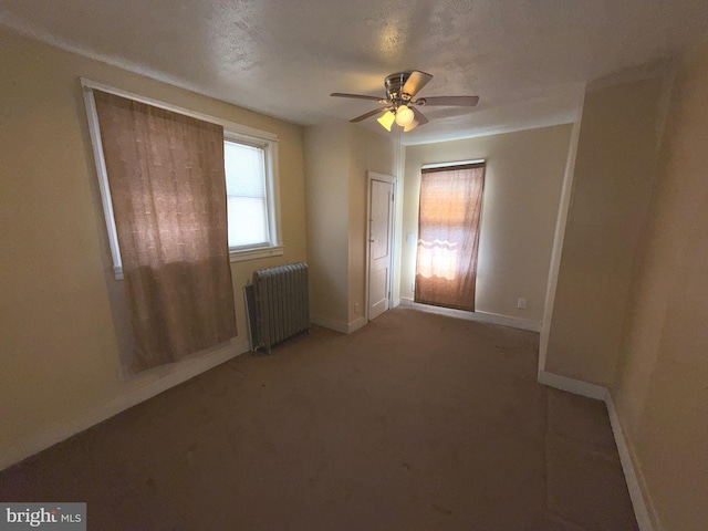 carpeted spare room featuring baseboards, radiator, and ceiling fan