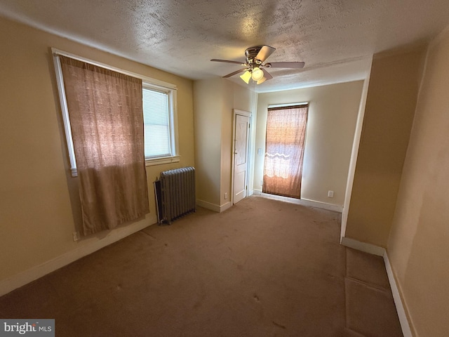 unfurnished bedroom featuring baseboards, multiple windows, radiator, and a textured ceiling