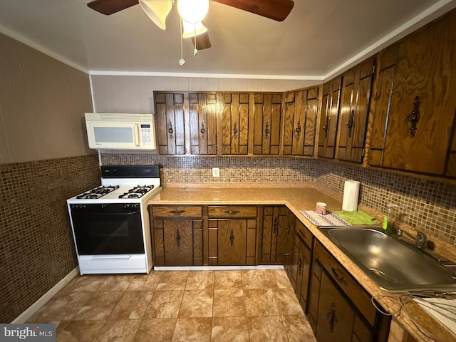 kitchen featuring white appliances, light countertops, decorative backsplash, a sink, and ceiling fan