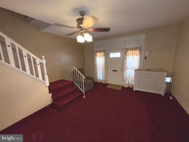 carpeted entryway featuring stairway and a ceiling fan