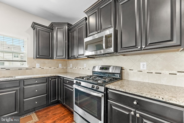 kitchen featuring stainless steel appliances, dark wood-style floors, and dark cabinetry