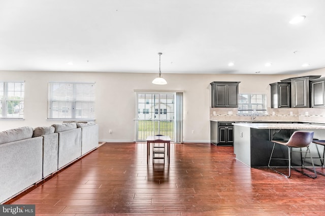 kitchen with decorative backsplash, open floor plan, a breakfast bar, and a sink
