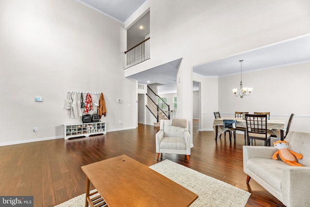 living room featuring stairway, an inviting chandelier, ornamental molding, and wood-type flooring