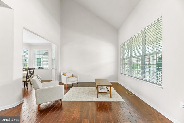 living area featuring visible vents, baseboards, high vaulted ceiling, and dark wood finished floors