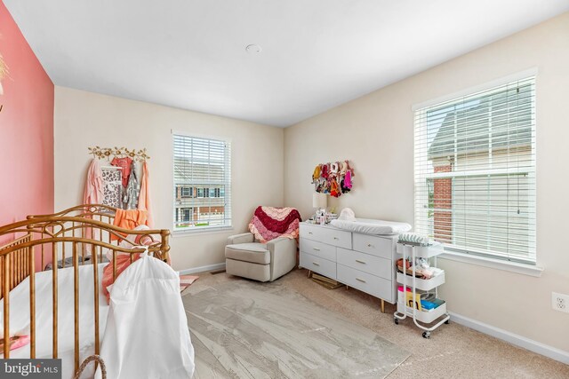 bedroom featuring baseboards, carpet flooring, and a crib