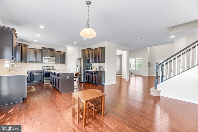 kitchen with recessed lighting, dark wood finished floors, stainless steel appliances, a kitchen island, and pendant lighting