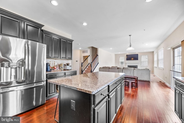 kitchen with open floor plan, stainless steel fridge, dark wood finished floors, and a kitchen island