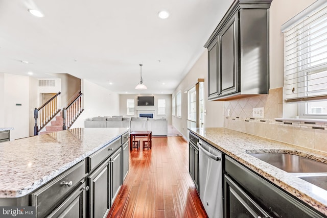 kitchen featuring dishwasher, a wealth of natural light, wood finished floors, and a fireplace