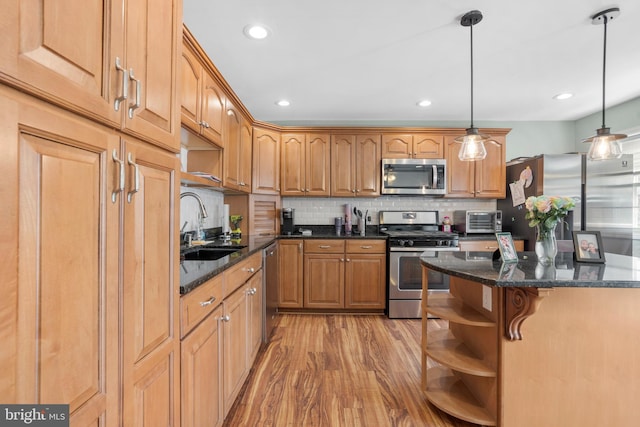 kitchen with dark stone counters, a sink, open shelves, light wood-type flooring, and appliances with stainless steel finishes