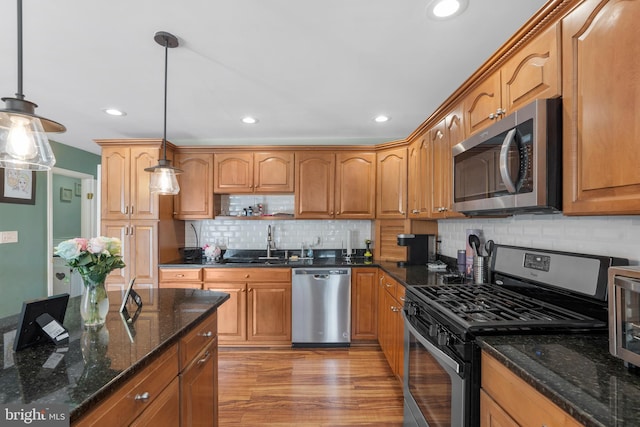 kitchen featuring recessed lighting, stainless steel appliances, decorative light fixtures, backsplash, and a sink