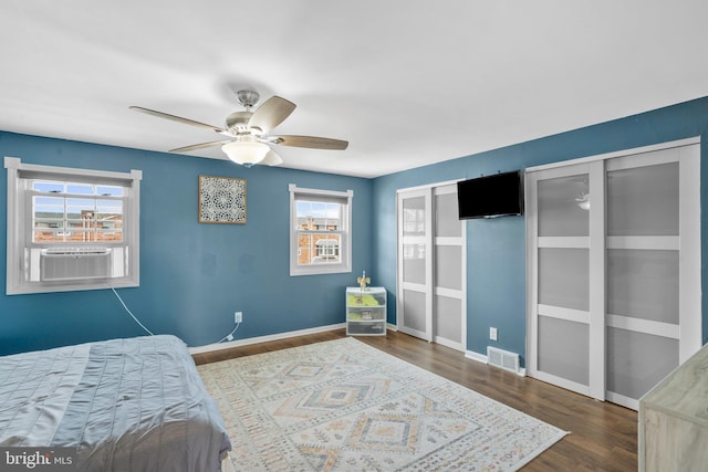 bedroom with visible vents, a ceiling fan, baseboards, wood finished floors, and cooling unit