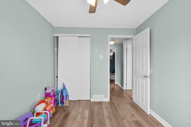 recreation room with wood finished floors, ceiling fan, visible vents, and baseboards