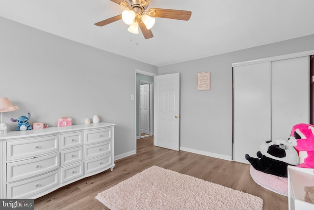 bedroom featuring a closet, a ceiling fan, wood finished floors, and baseboards