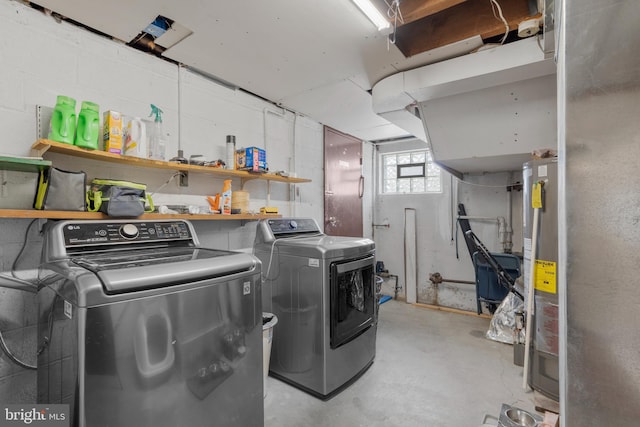 laundry room featuring washer and dryer, water heater, concrete block wall, and laundry area