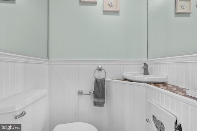 bathroom featuring a wainscoted wall, toilet, and vanity
