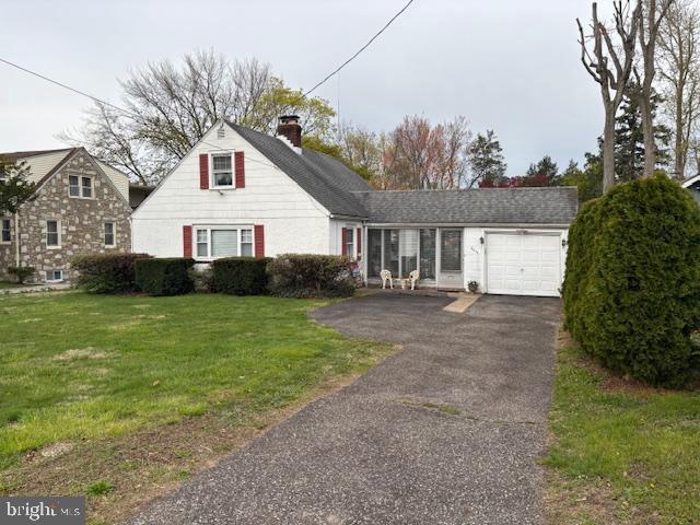 view of front of property with a chimney, a garage, a front yard, and driveway