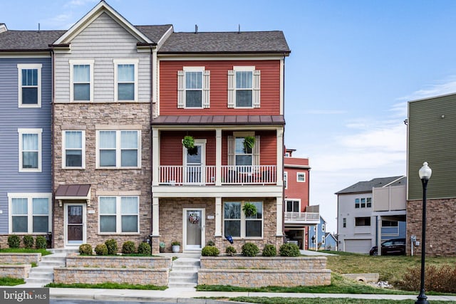 townhome / multi-family property featuring metal roof, stone siding, a standing seam roof, and a balcony