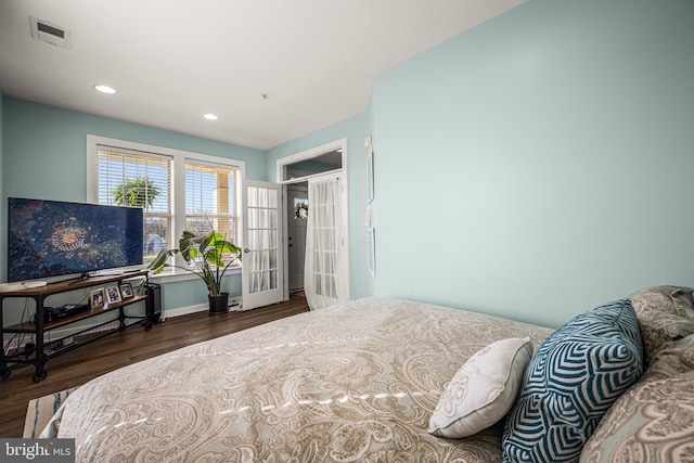bedroom with baseboards, wood finished floors, visible vents, and recessed lighting