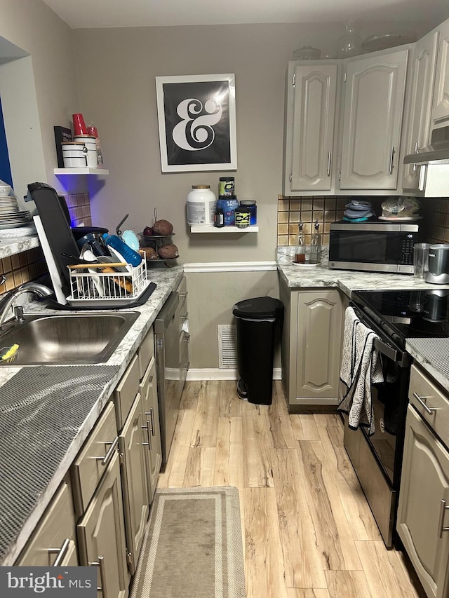 110 Woodland Ave, Norwood, PA 19074 - kitchen featuring decorative backsplash, a sink, light countertops, light wood finished floors, and stainless steel appliances