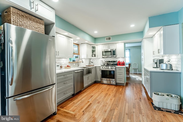 kitchen featuring tasteful backsplash, light wood finished floors, light countertops, appliances with stainless steel finishes, and gray cabinetry