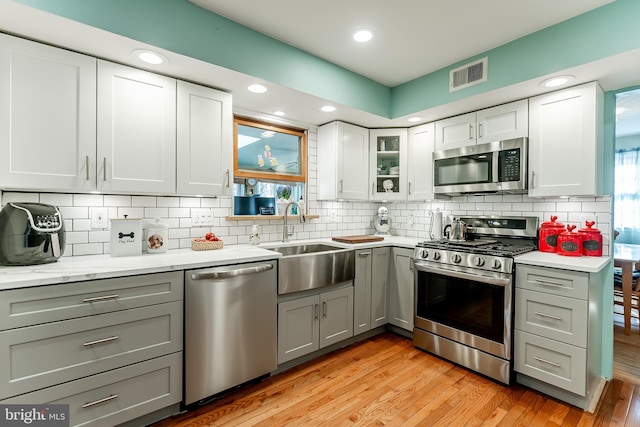 kitchen with gray cabinets, stainless steel appliances, visible vents, and a sink