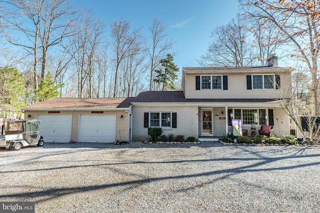 traditional-style home with a chimney, an attached garage, a porch, gravel driveway, and brick siding