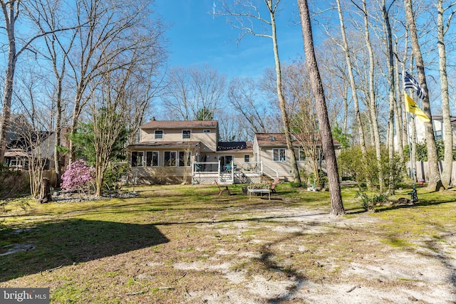 rear view of house featuring a yard, a chimney, a deck, and a shingled roof