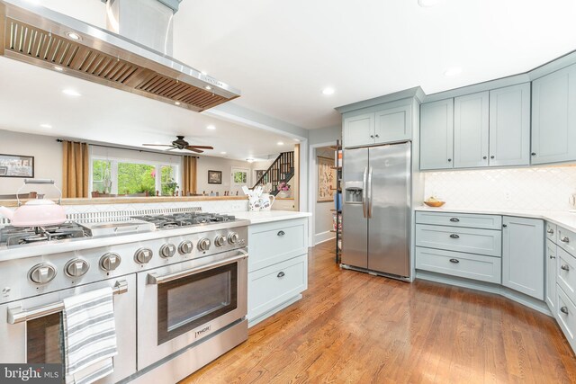 90 Indiantown Rd, Glenmoore, PA 19343 - kitchen with stainless steel appliances, wall chimney exhaust hood, light wood-style floors, light countertops, and backsplash