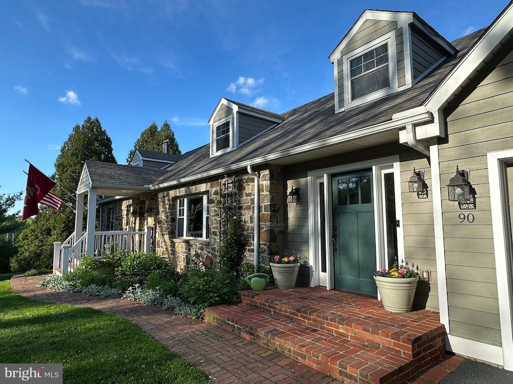 doorway to property with covered porch and stone siding