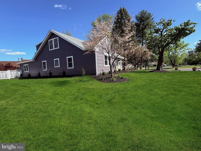 view of side of home with fence and a yard