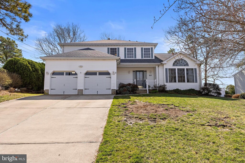 203 Riptide Ave, Manahawkin, NJ 08050 - traditional home featuring a garage, a porch, concrete driveway, and a front lawn
