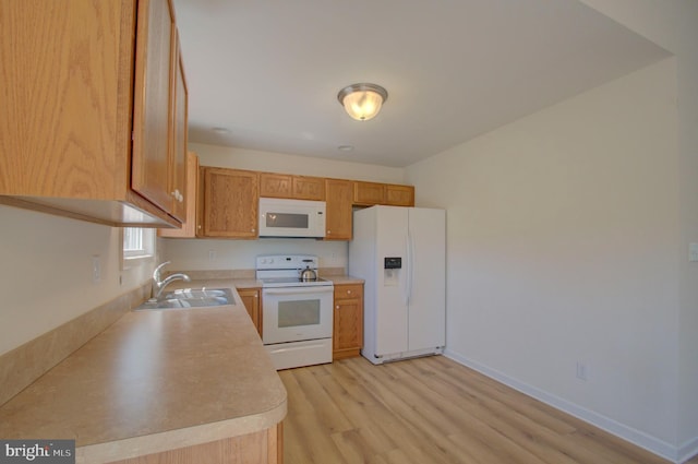 kitchen with a sink, light countertops, baseboards, light wood-type flooring, and white appliances