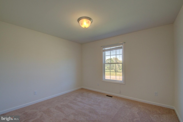 spare room featuring visible vents, baseboards, and light carpet