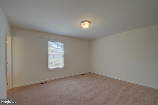 empty room with visible vents, light colored carpet, and baseboards